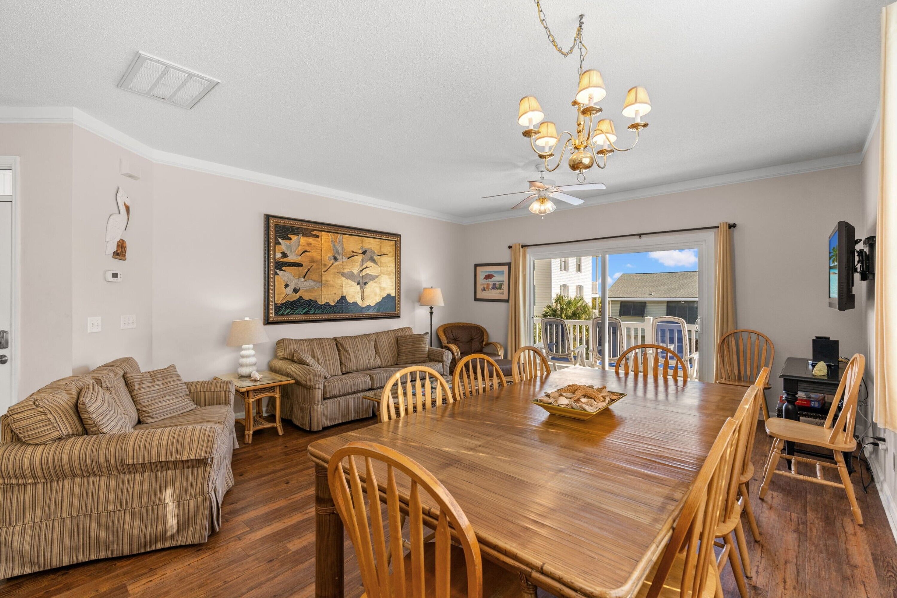 A dining area with a wooden table and chairs, a chandelier, and a painting on the wall.
