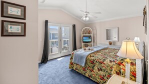A bedroom with a bed, a ceiling fan, a TV, and a view of the outside. - 'BIKINI BOTTOM' OCEANSIDE OF BLVD, GREAT VIEWS,POOL, 5 Bedroom, 5 Bathrooms (Surfside Beach)