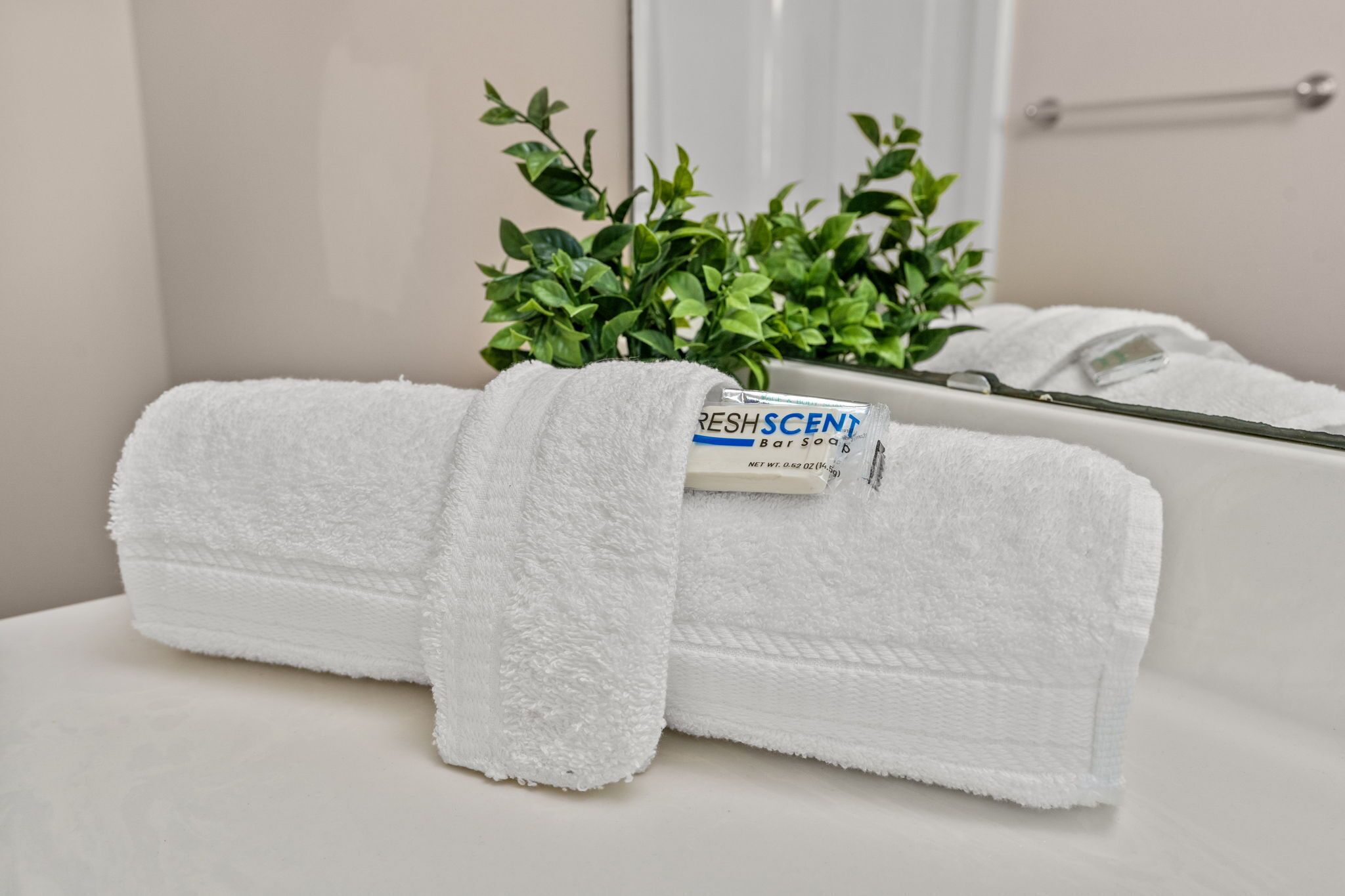 Un asciugamano bianco piegato con cura con un'etichetta su un ripiano del bagno.