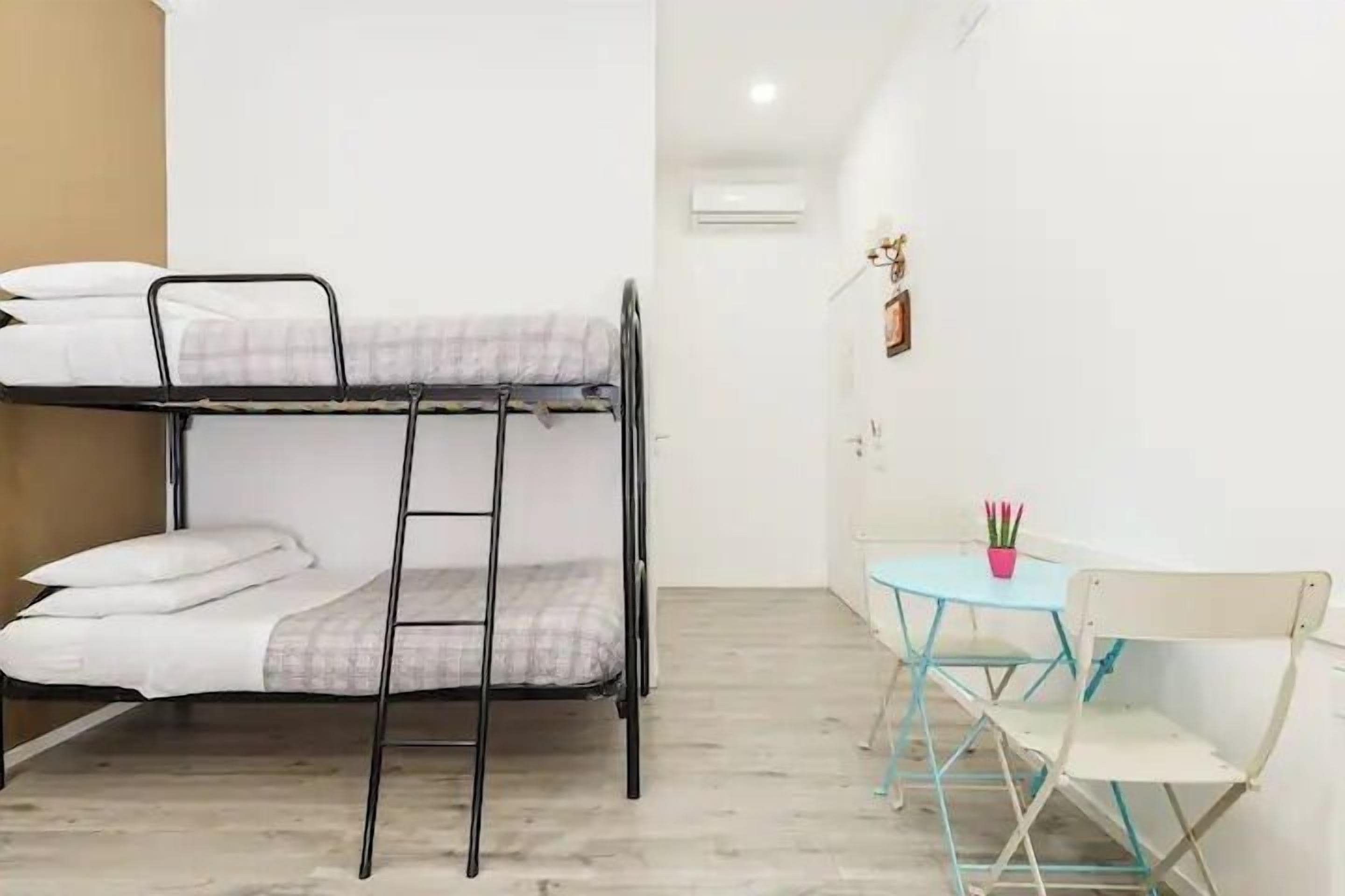 A bunk bed with a ladder, a small table with chairs, and a potted plant.