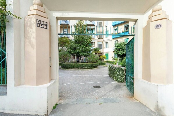 A gated entrance to a residential building with a paved driveway leading to a courtyard. - B&B Don Mimì (Naples)