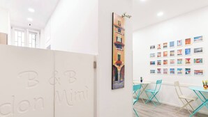 Un intérieur moderne avec un mur blanc, un grand tableau et une série de photos encadrées.