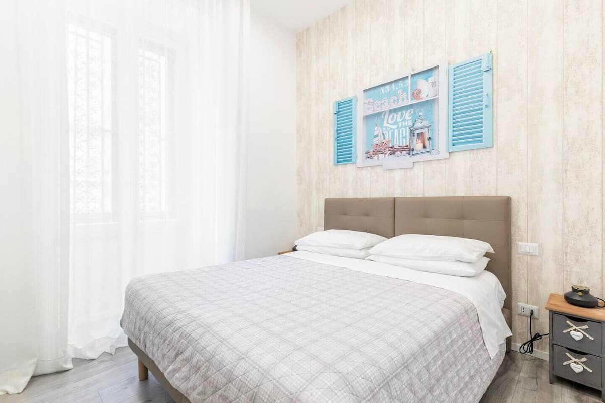 A bedroom with a bed, a nightstand, and a wall with a nautical-themed poster.