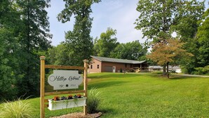 A sign for Hilltop Retreat with a grassy lawn and trees in the background.