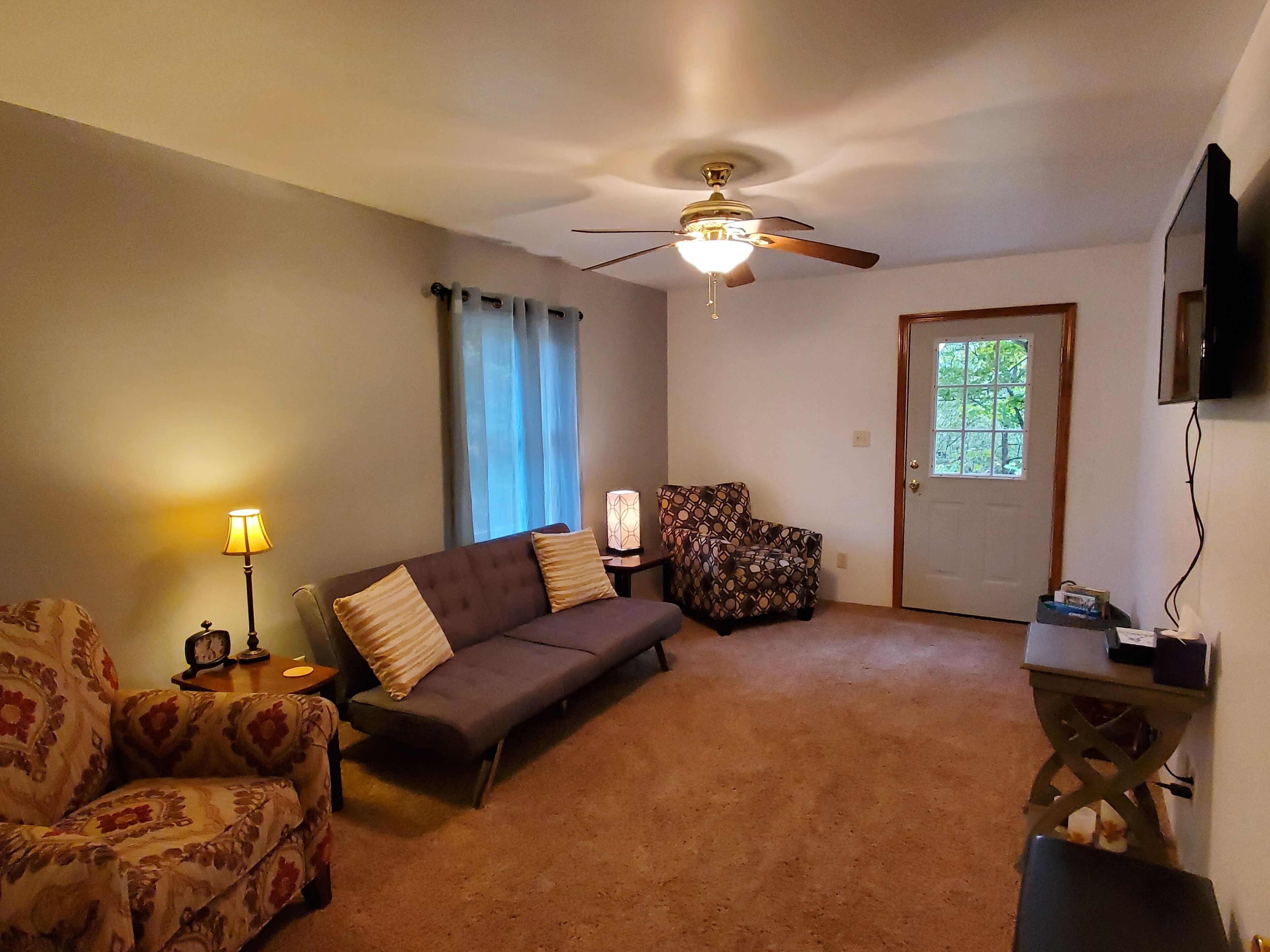 A living room with a sofa, armchair, and a ceiling fan.
