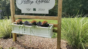 A wooden sign with the text "Hilton Retreat Est. 2019" mounted on a wooden frame.