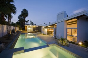 Uma área de piscina moderna, com piscina transparente, espreguiçadeiras e um edifício com os dizeres 'LOVE' e 'GOAL'.