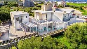 A modern building with multiple levels, outdoor seating areas, and a view of a mountainous landscape. - Elia Tree Studios (Heraklion)