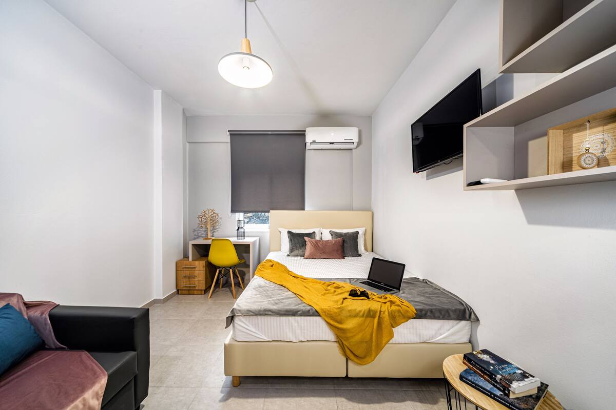 A modern bedroom with a bed, a desk, a chair, and a bookshelf.