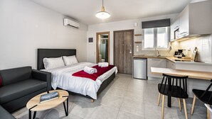 A modern hotel room with a bed, a sofa, a desk, and a kitchenette. - Elia Tree Studios (Heraklion)