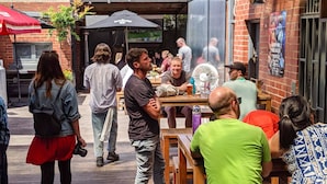 Un espace extérieur aménagé pour les repas, avec des murs en briques et des tables en bois.