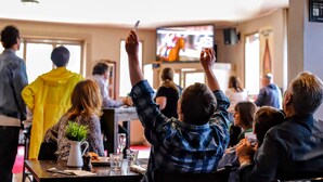 Un groupe de personnes se trouve dans un restaurant, et on peut voir un téléviseur à l’arrière-plan.