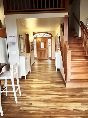 Stunning hallway with traditional design, featuring a door with a stained glass window, white cabinetry, and a wooden staircase.