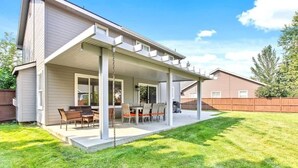 A covered patio with outdoor furniture, a concrete floor, and a wooden fence in the background. - Upscale House for 17 with Firepit & Lovely Yard (Star)