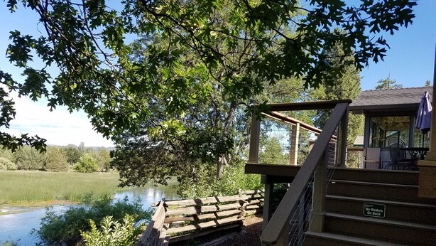 A wooden deck with a sign prohibiting wading, overlooking a lake with a gazebo and outdoor seating. -  Cassel, Ca. on Hat Creek. Close/Baum Lake, Burney, Mt. Shasta/Lassen 3 nite min (Cassel)
