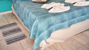 A bedroom with a tufted headboard, teal walls, a ceiling fan, and a bed with a blue checkered bedspread and decorative pillows. - Arroyo Suite House (Nono)