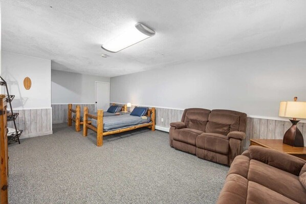 A room with a bed, two brown sofas, a lamp, and a ceiling light.