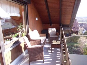 A covered outdoor seating area with wicker furniture and a view of the surrounding landscape. - Apartment Angela (Bad Sachsa)