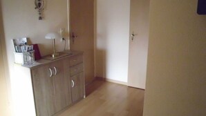 A room with a wooden cabinet, a desk with a lamp, and a door leading to another room. - Apartment Angela (Bad Sachsa)