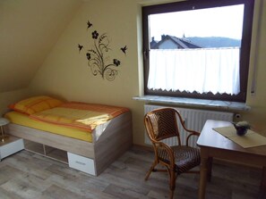 Quarto com cama, cadeira, janela e radiador.