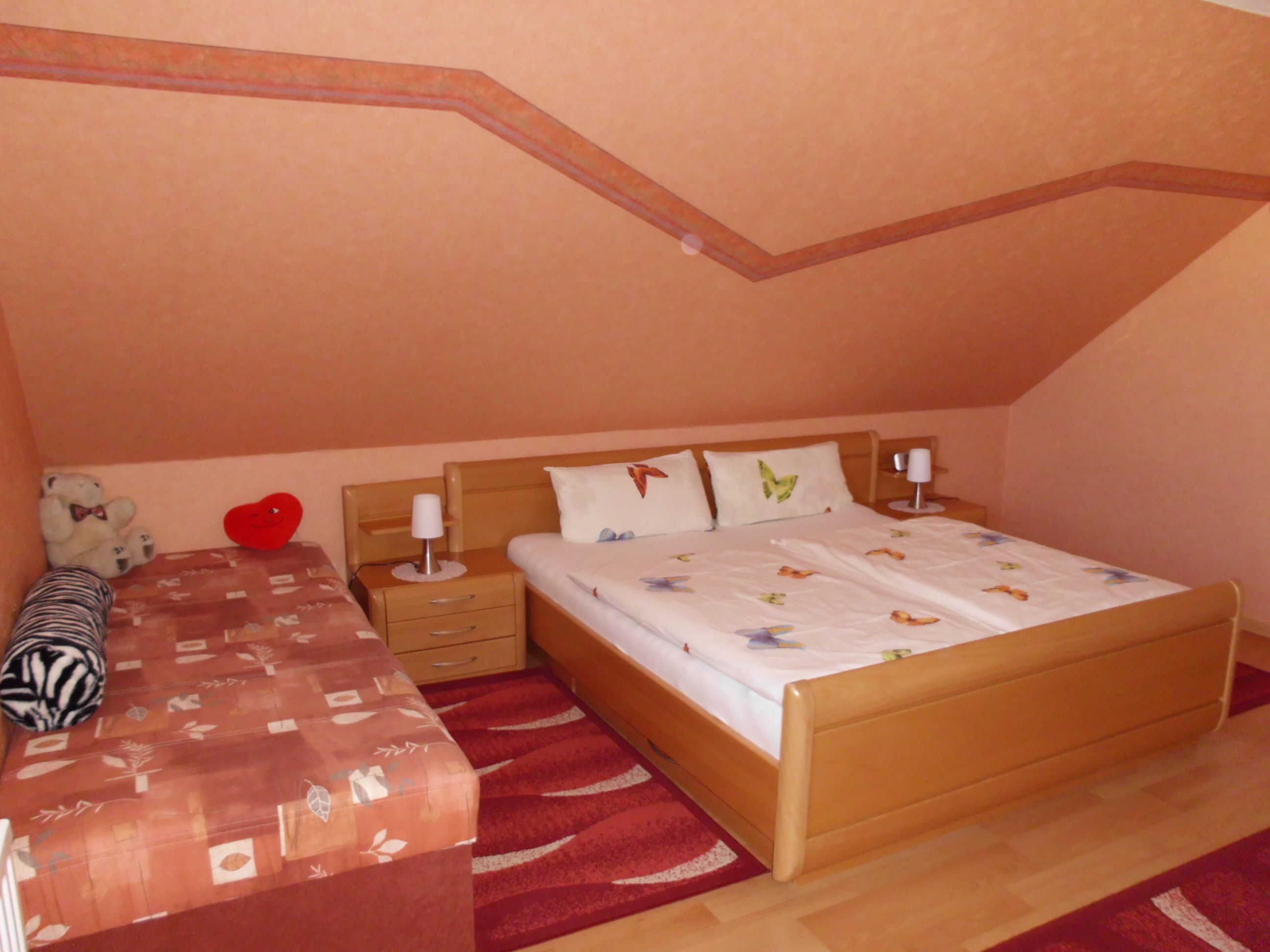 A bedroom with a bed, bedside tables, a bench, and a teddy bear.
