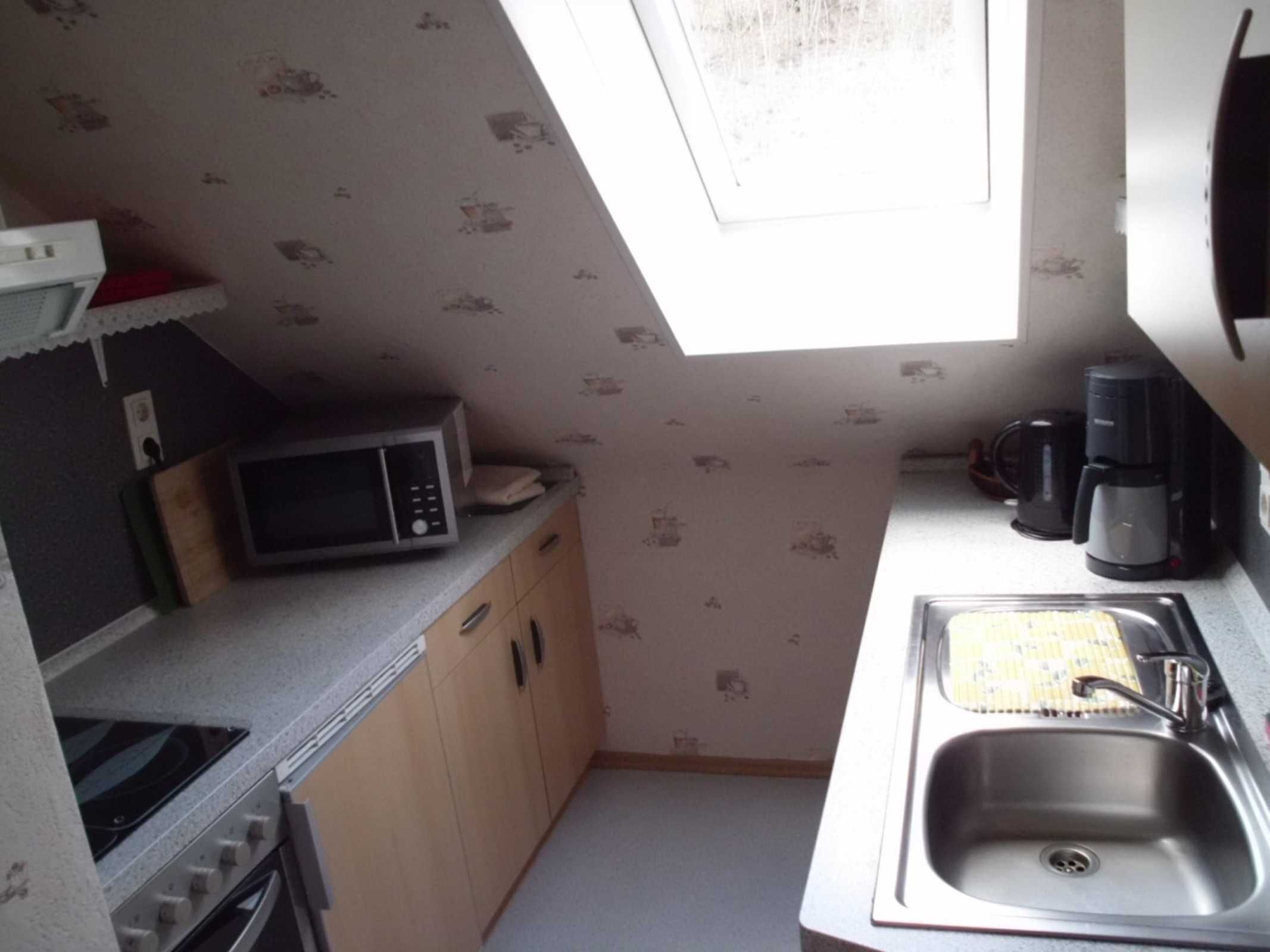 Cocina compacta con microondas, cafetera y lavabo.