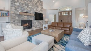 A living room with a stone fireplace, leather sofa, and a television mounted on the wall.