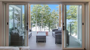 A deck with wicker furniture and a table, overlooking a tree-lined area.