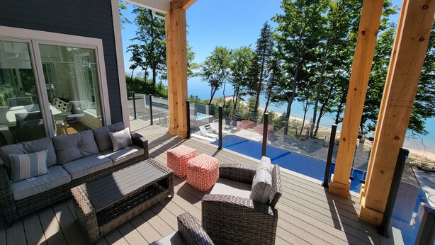 A covered outdoor area with a pool, wicker furniture, and a view of the beach.