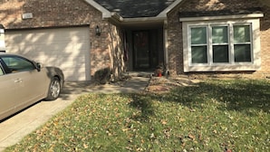 A two-story house with a garage, a front porch, and a brick exterior.