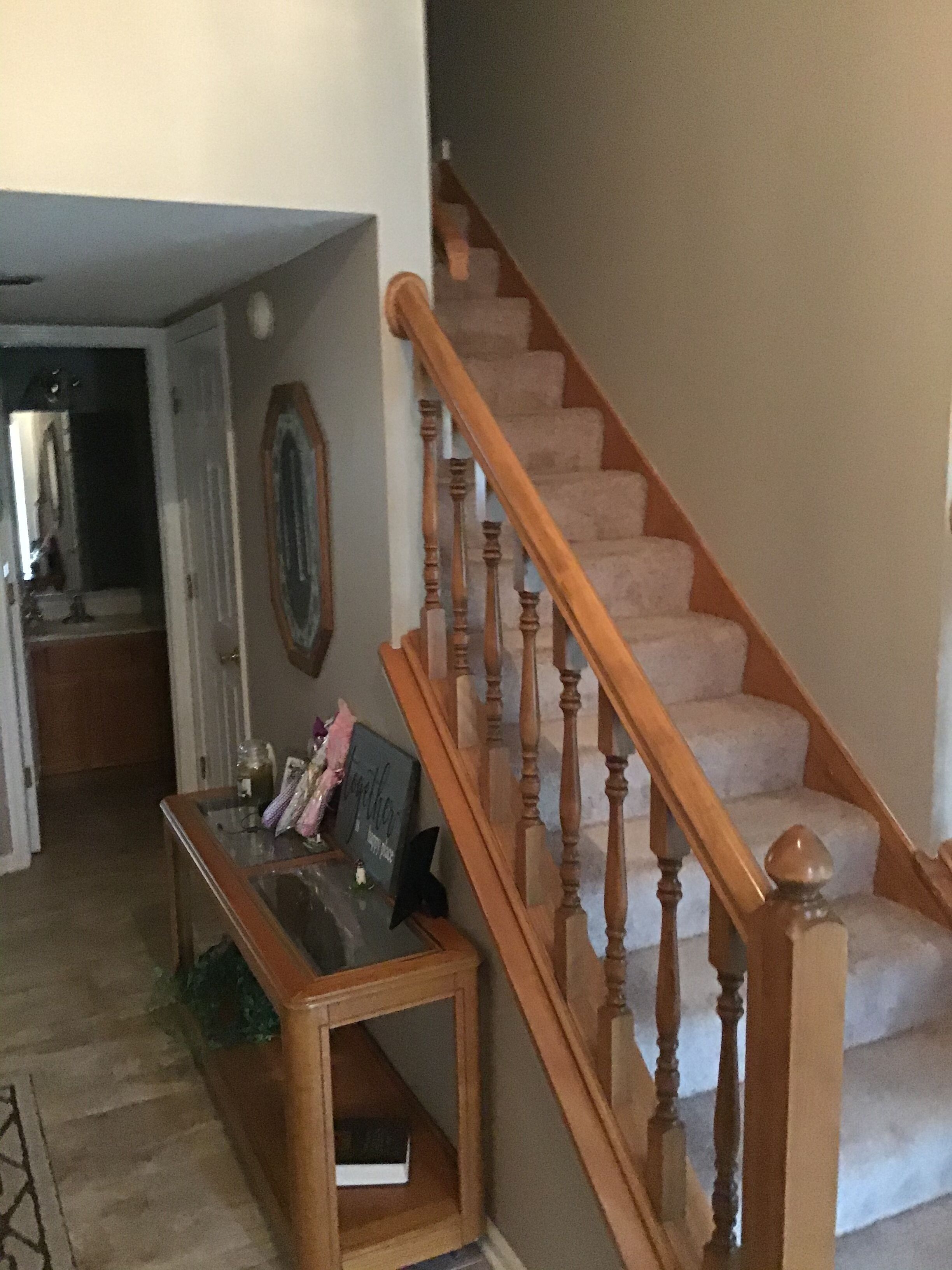 Una escalera de madera con barandillas y peldaños alfombrados, que conduce a un piso superior.