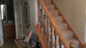 A staircase with wooden balusters and carpeted steps, leading to an upper floor.
