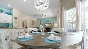 A dining area with a round table set for four, surrounded by white chairs. - Disney Home, Huge Patio 6B/4B -Pool& SPA-FREE HEAT (Kissimmee)