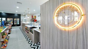 A modern interior with a central counter, refrigerated display cases, and a decorative illuminated sign. - Disney Home, Huge Patio 6B/4B -Pool& SPA-FREE HEAT (Kissimmee)