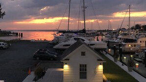 Un puerto deportivo al atardecer con barcos amarrados, un edificio blanco en primer plano y un cielo nublado.