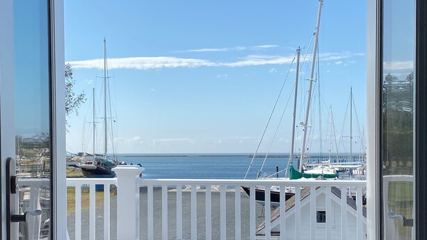 Vista desde un balcón con baranda blanca, sobre un puerto deportivo con varios veleros amarrados.
