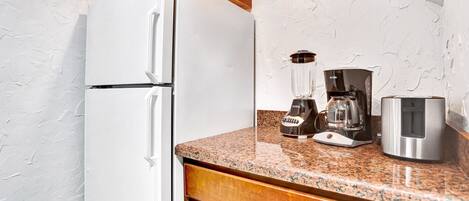 A kitchen with a white refrigerator, a coffee maker, and a blender on the counter.