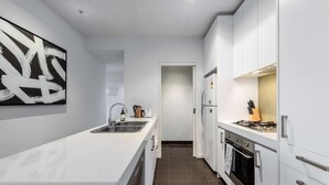 Una cocina moderna con una isla central, electrodomésticos de acero inoxidable y un cuadro abstracto grande en la pared.