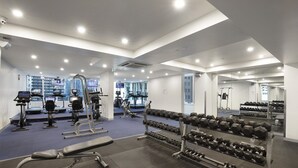Un gimnasio moderno con diversos equipos de ejercicio, incluyendo cintas de correr, bicicletas estáticas y máquinas de pesas.