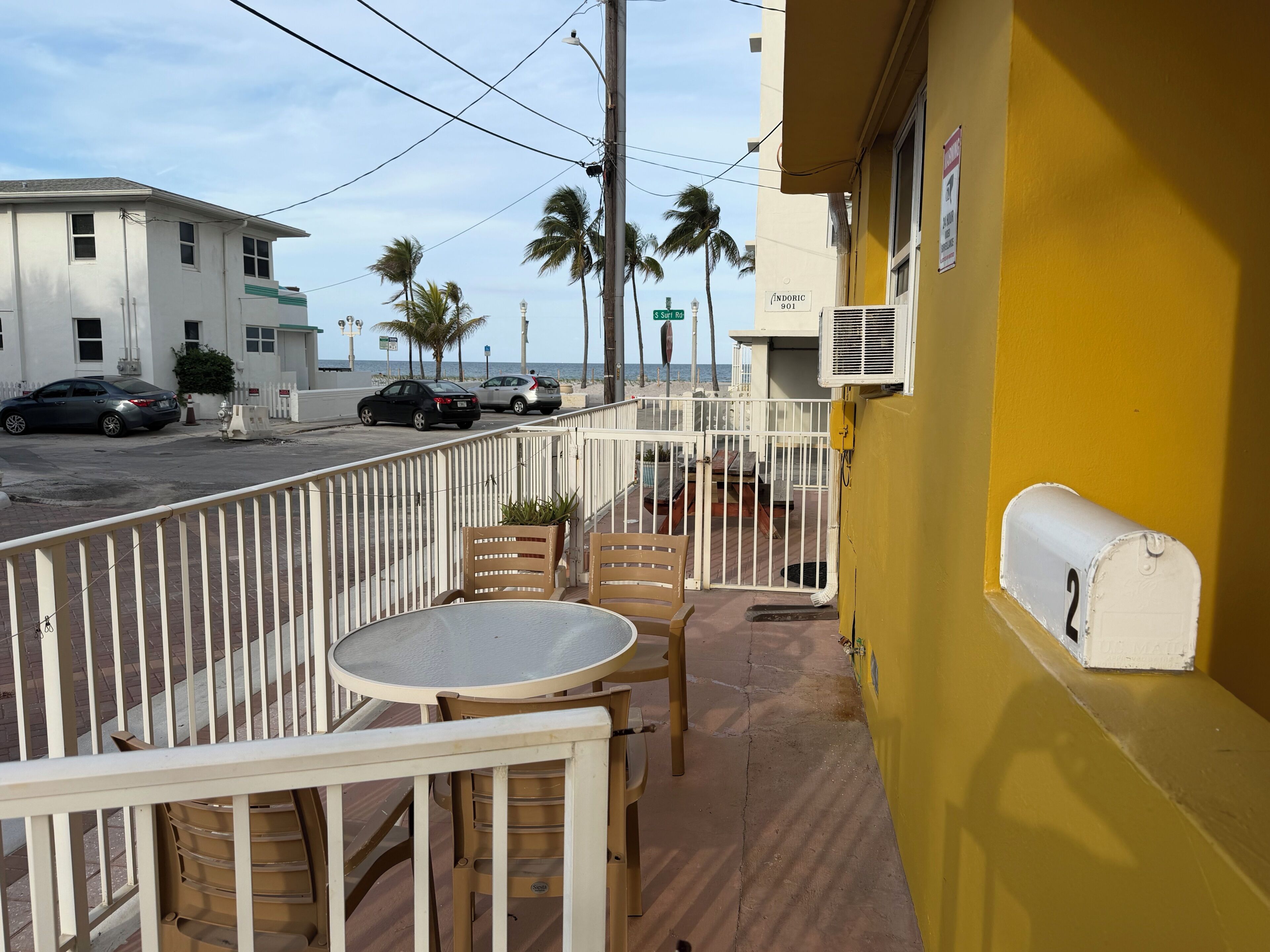 A balcony with a white railing, a small table, and two chairs.