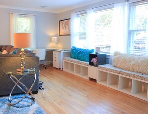 Een moderne woonkamer met een glazen bureau, een bank met een zacht kussen en een boekenplank.
