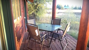 En träaltan med ett glasbord och metallstolar.