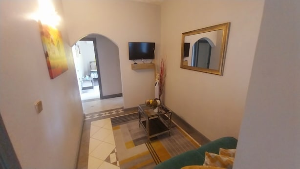 Ein Flur mit Fernseher, Spiegel und einem kleinen Tisch mit einer Vase.