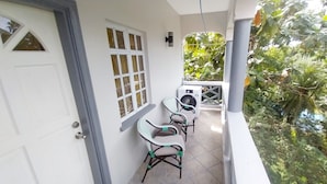 Ein Balkon mit Waschmaschine, zwei Korbstühlen und einer Tür mit Fenster.