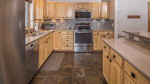 Una cocina moderna con armarios de madera, horno de acero inoxidable y salpicadero de azulejos.