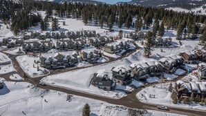 Una zona residencial cubierta de nieve con varias casas, caminos y una montaña al fondo.