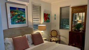 Une chambre à coucher bien rangée, avec un lit, une chaise, une lampe et une commode.