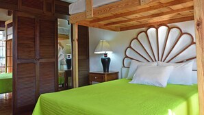 Een kamer met een stapelbed, een houten hoofdbord, een nachtkastje met een lamp en een groene sprei.
