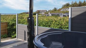 Ein Whirlpool auf einer Terrasse mit Blick auf Häuser und Grünflächen.