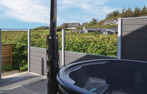 Ein Whirlpool auf einer Terrasse mit Blick auf Häuser und Grünflächen.